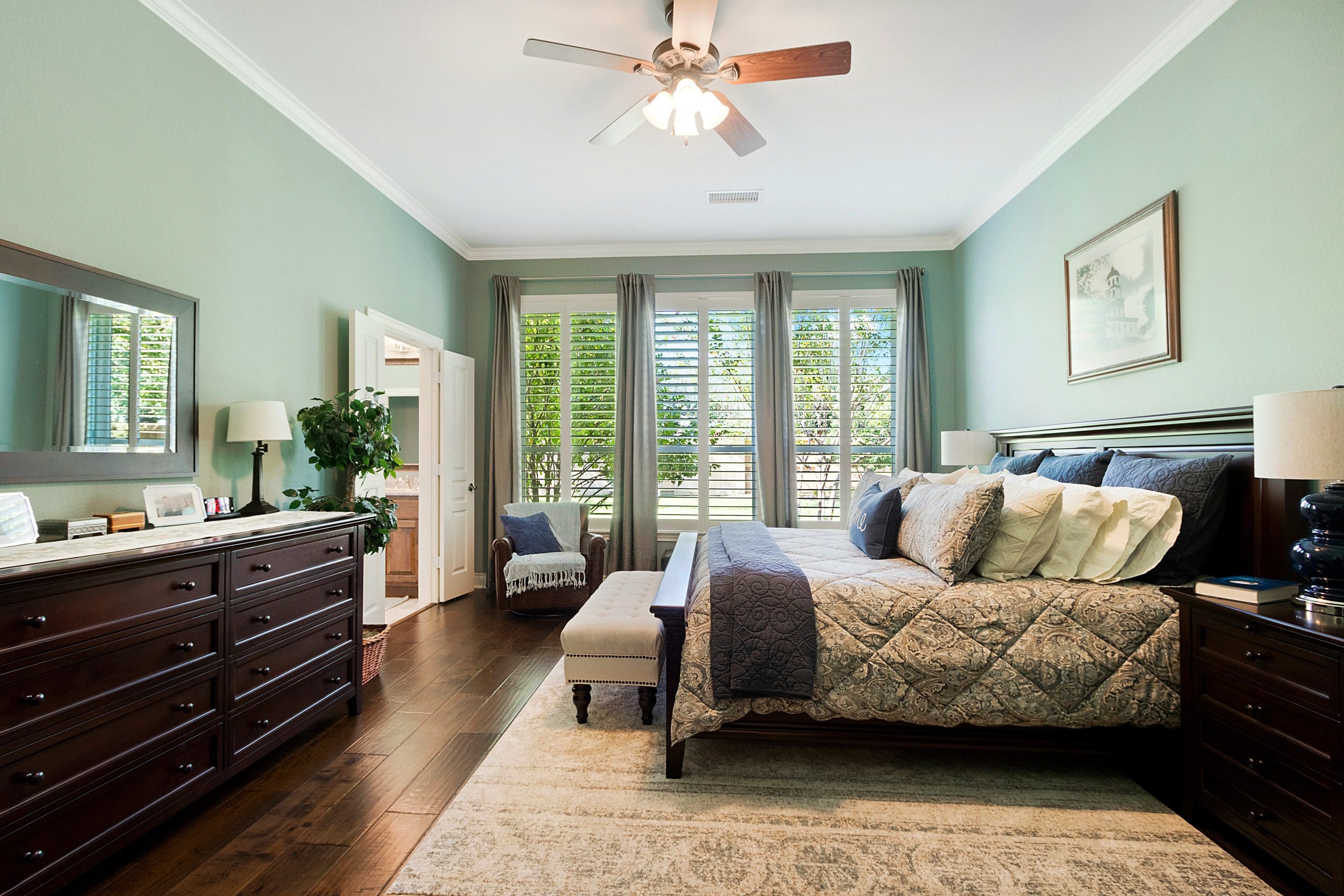 A bedroom with hardwood floors and a large bed.