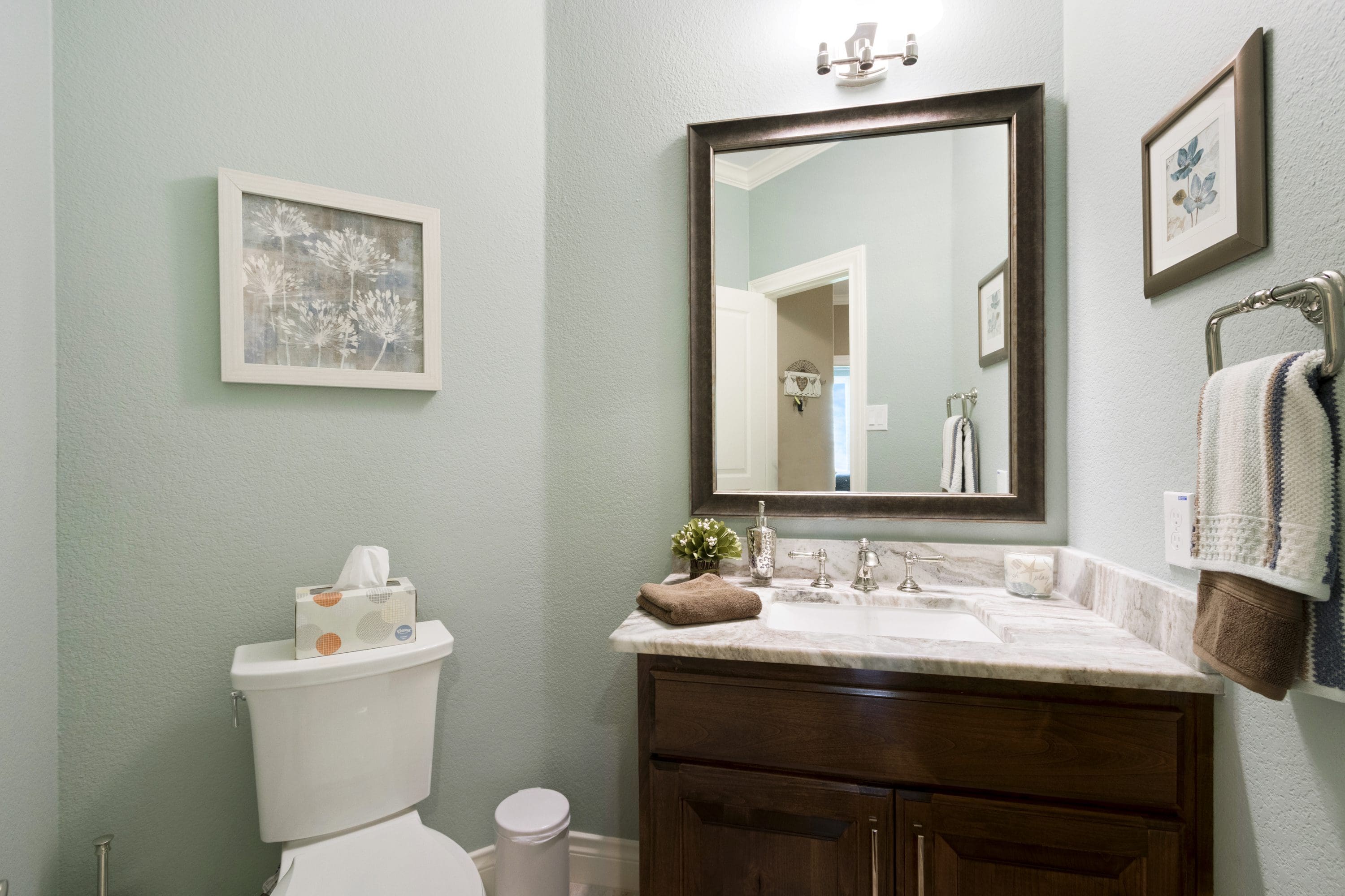 A bathroom with a toilet, sink and mirror.