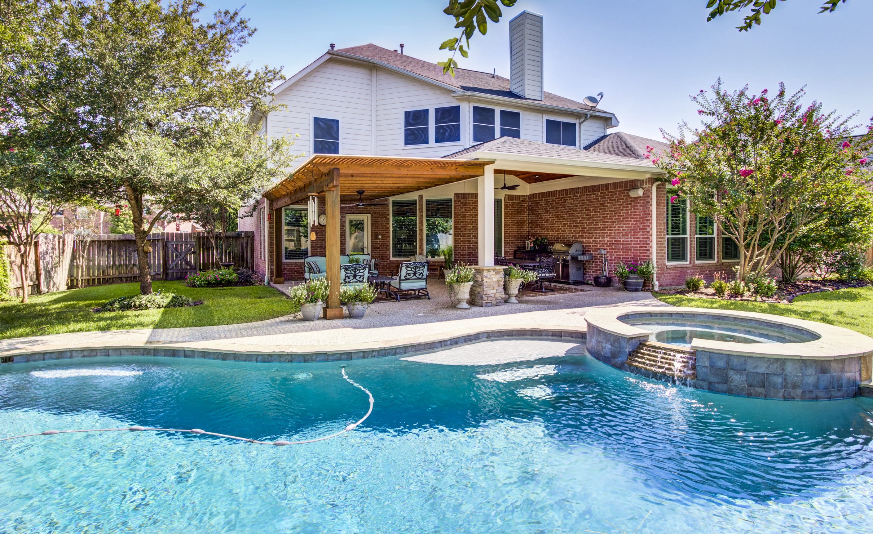 A pool with chairs and tables in the back yard.
