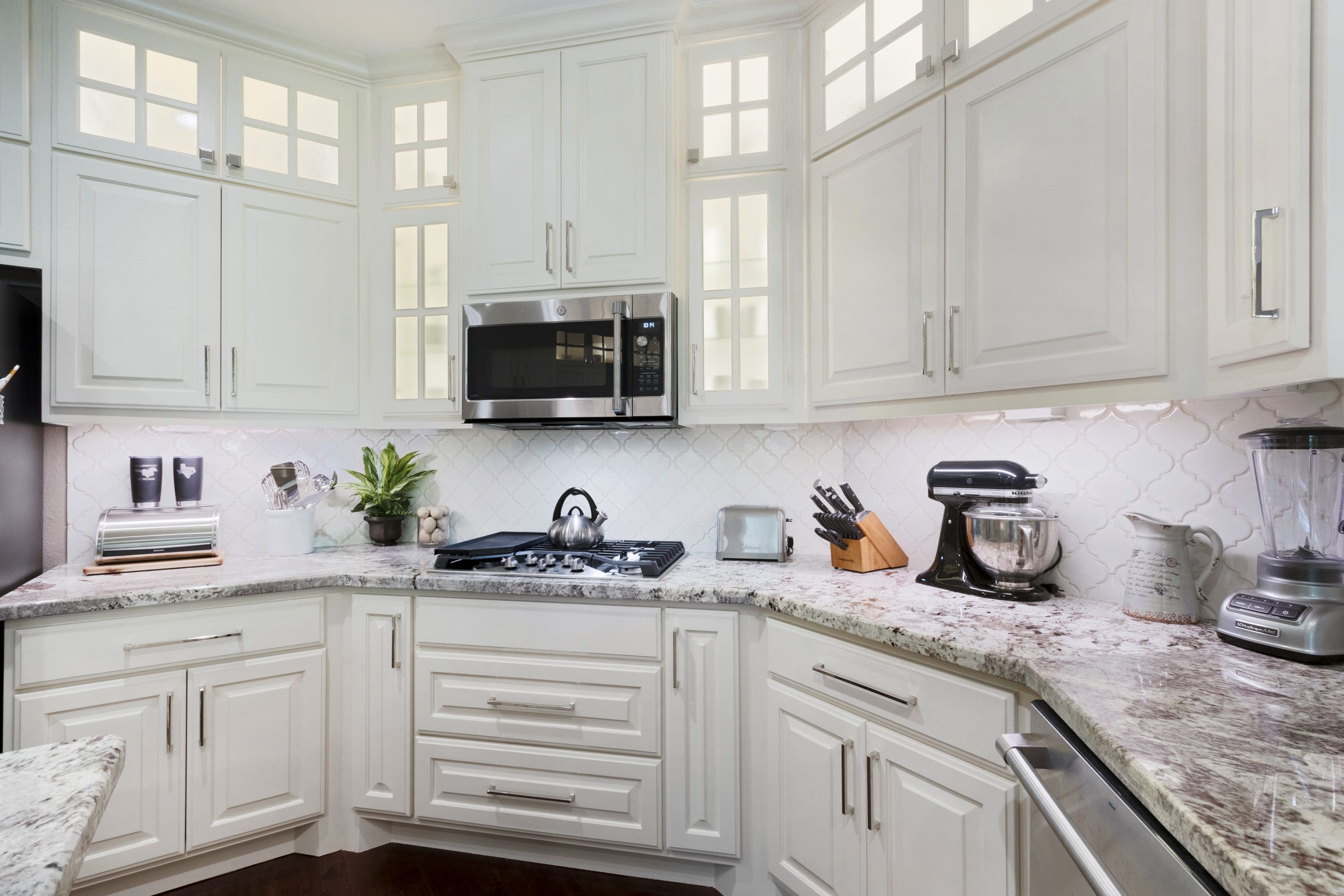 A kitchen with white cabinets and granite countertops.