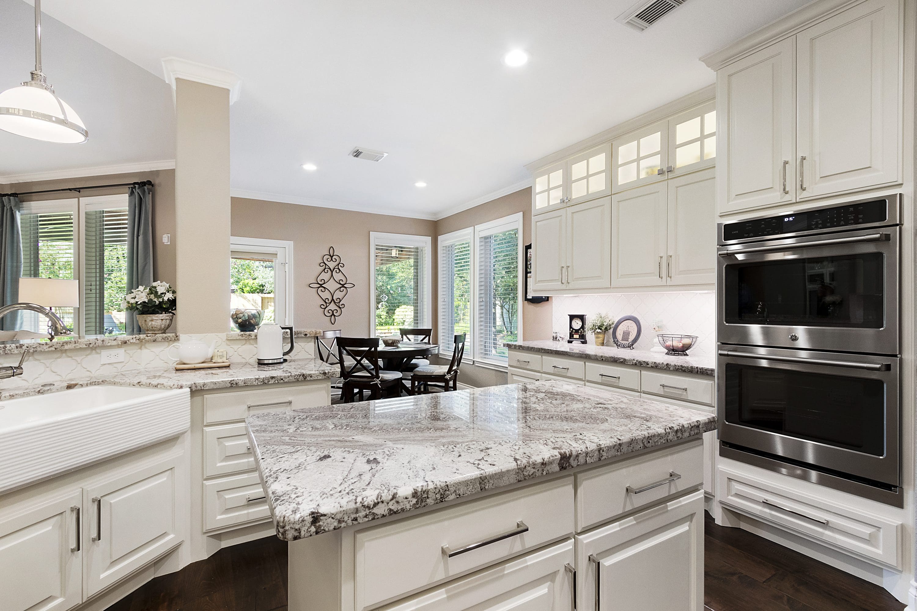A kitchen with white cabinets and granite counter tops.