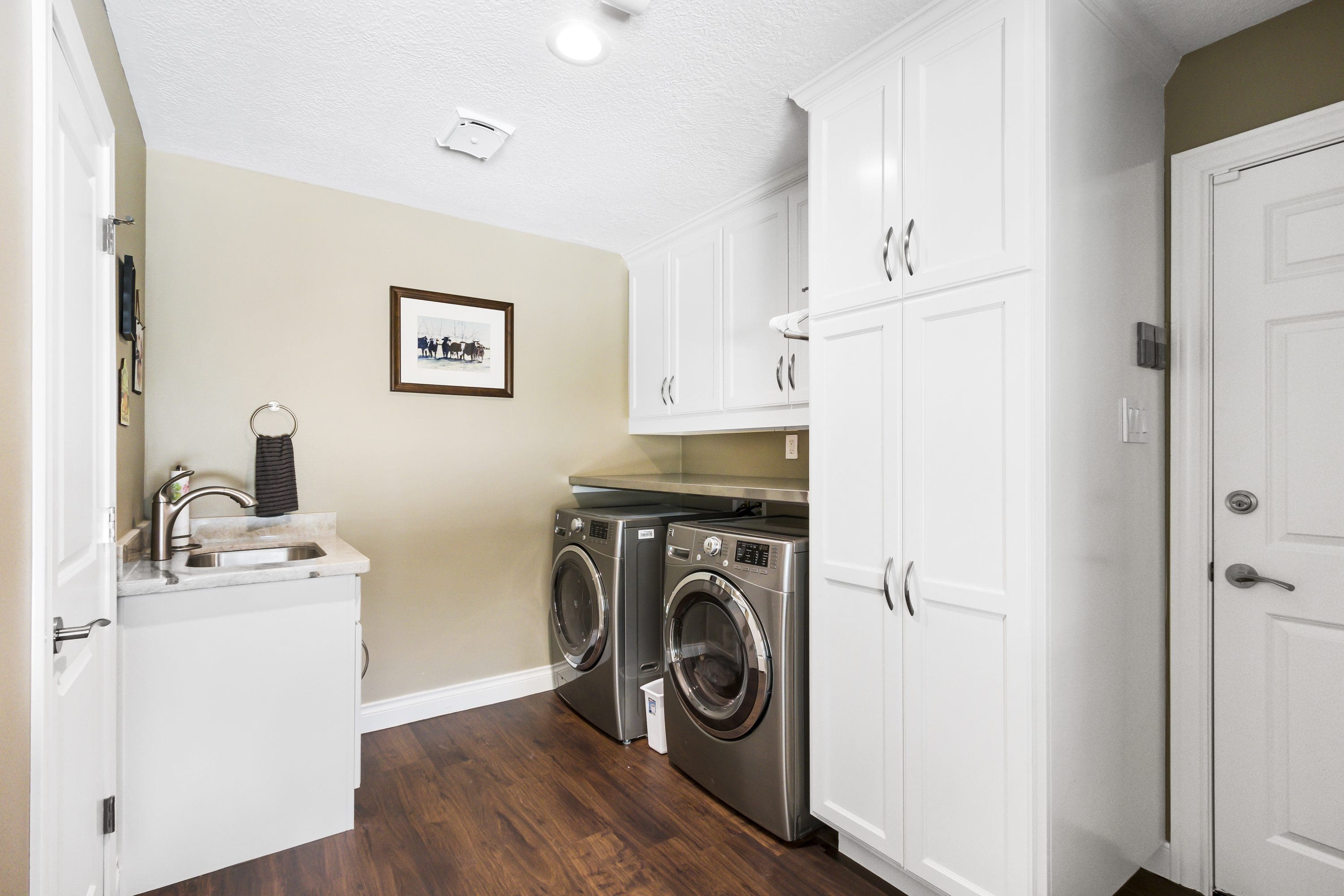 A laundry room with two machines and cabinets.