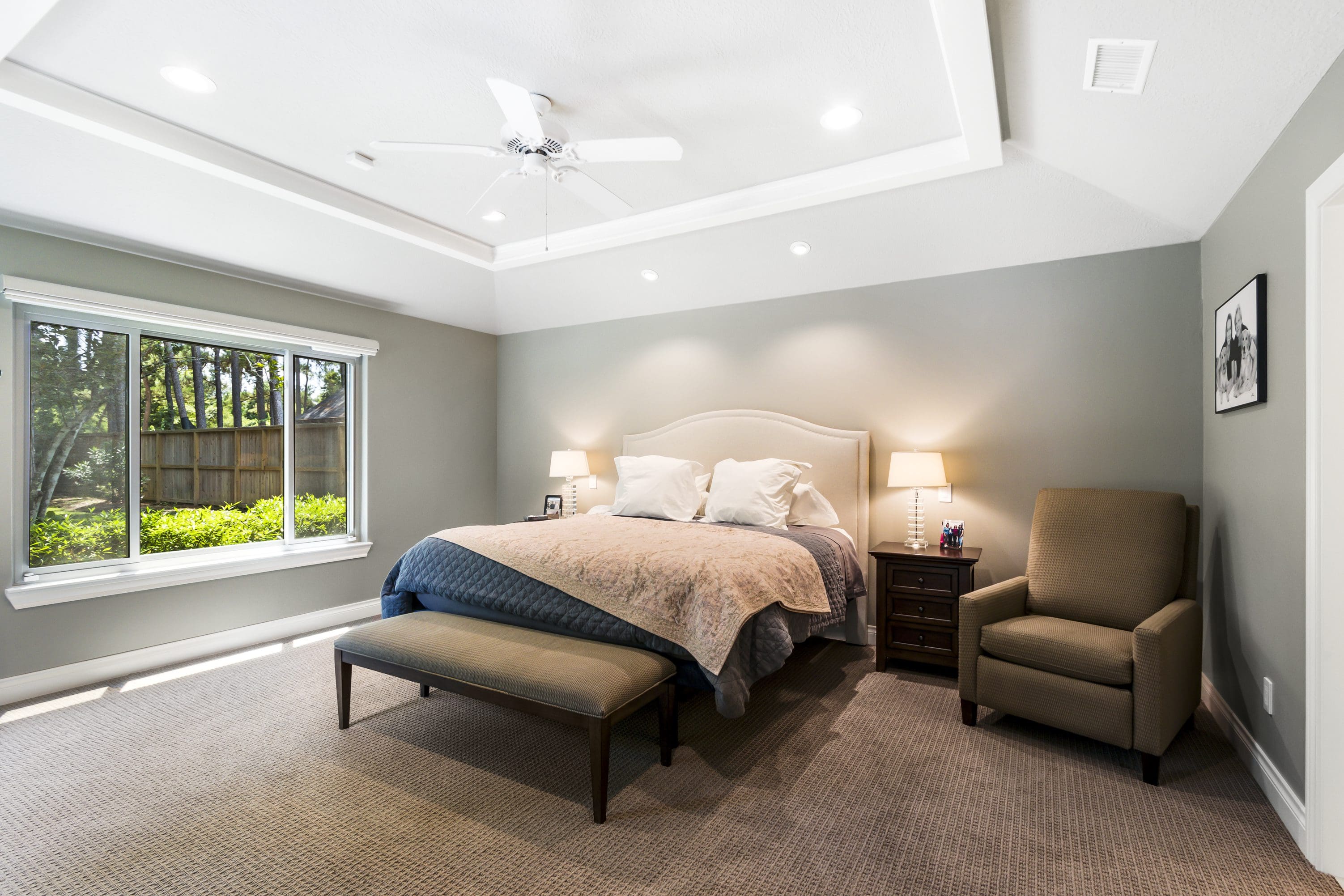A bedroom with a bed, two chairs and a window.