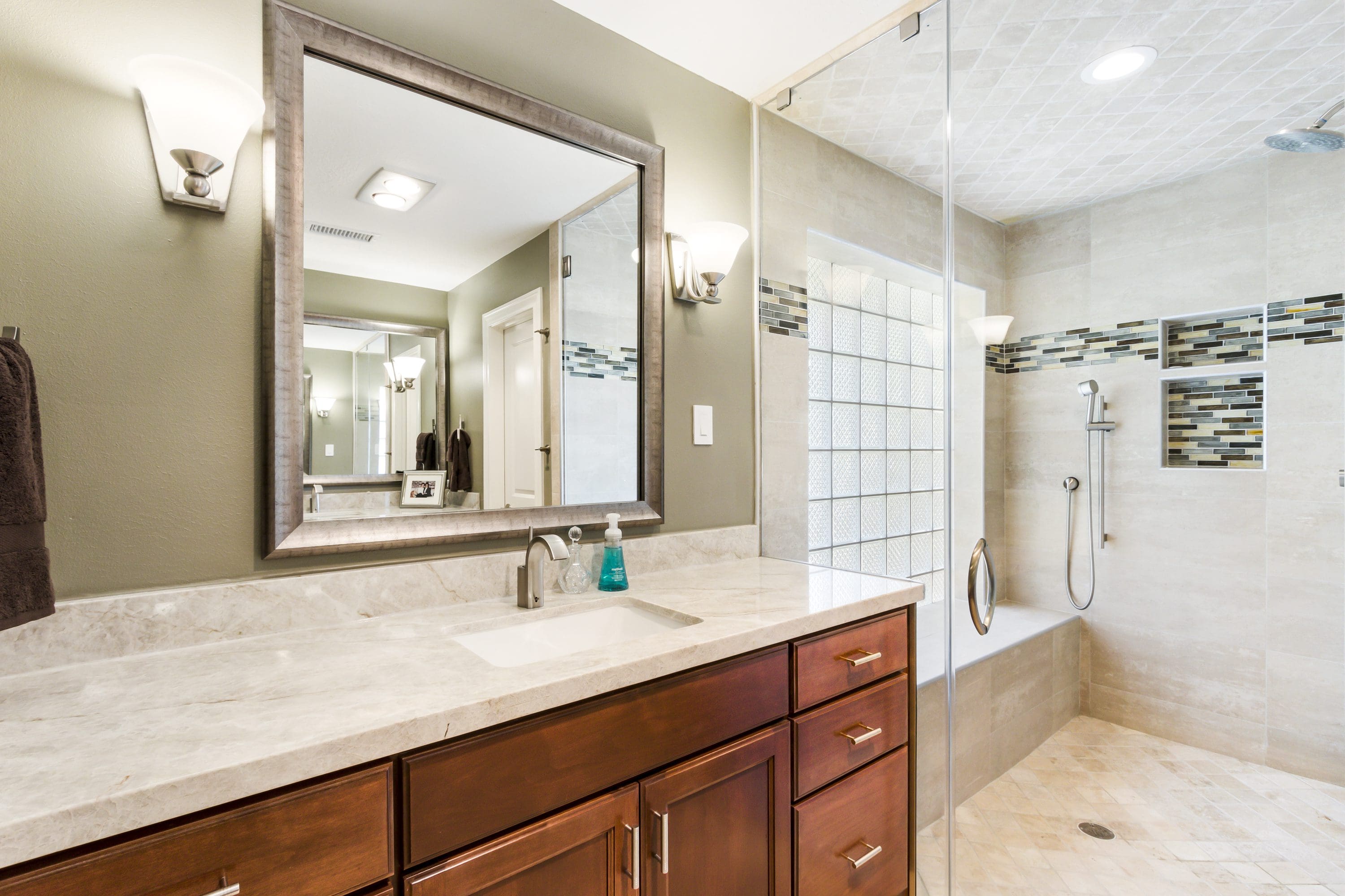 A bathroom with a large mirror and wooden cabinets.