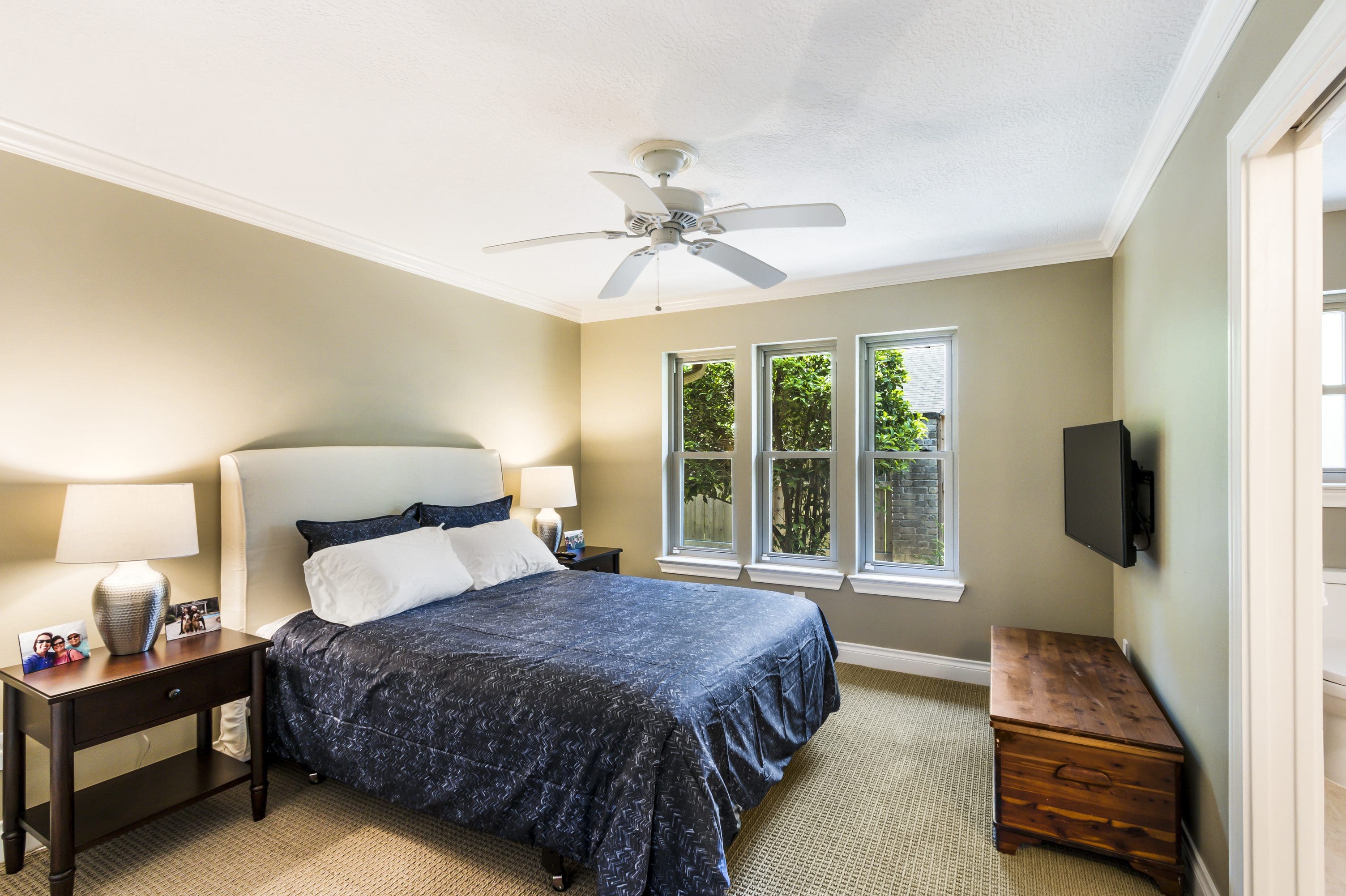 A bedroom with a bed, tv and dresser.