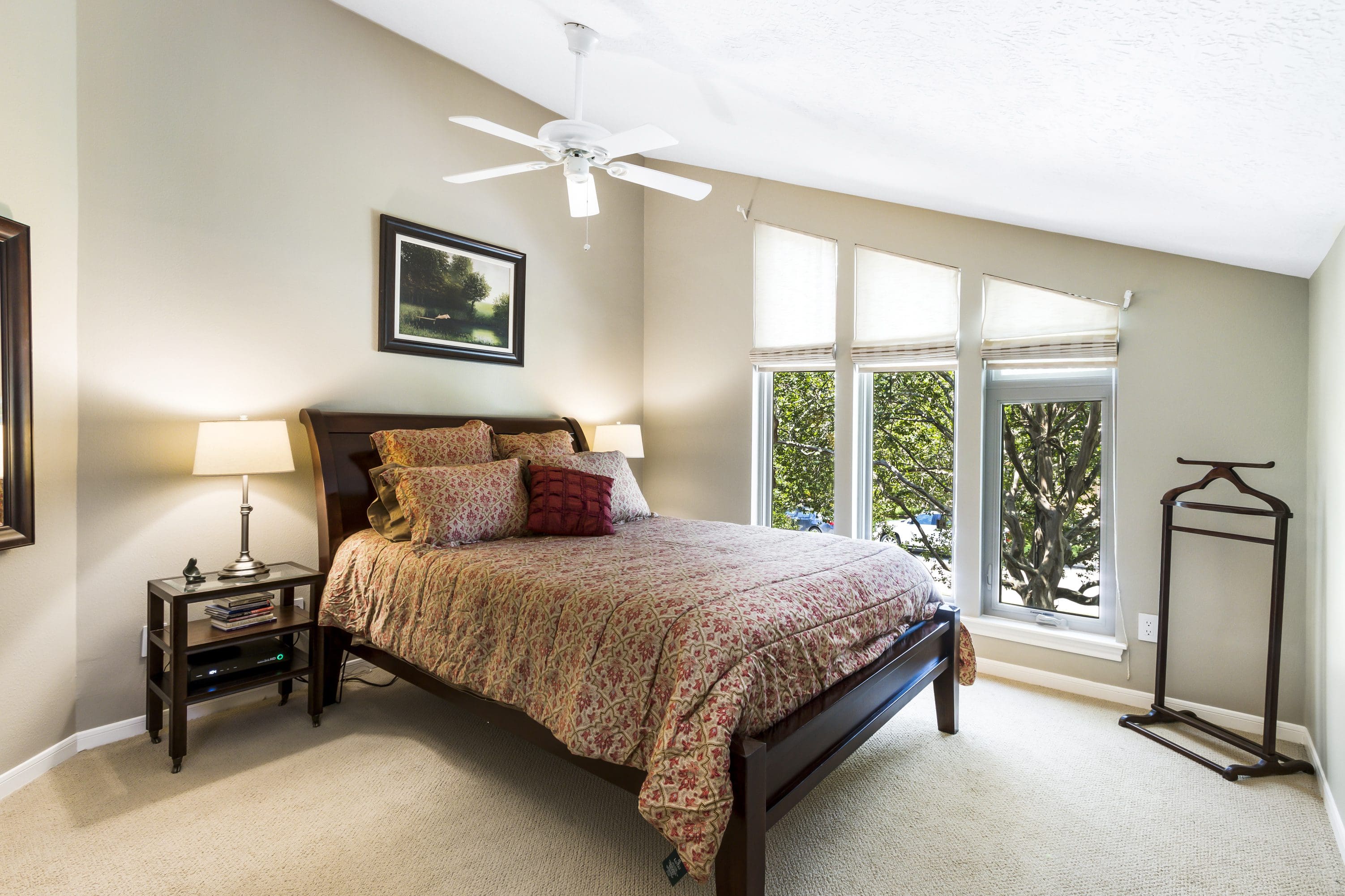 A bedroom with a bed, nightstand and window.