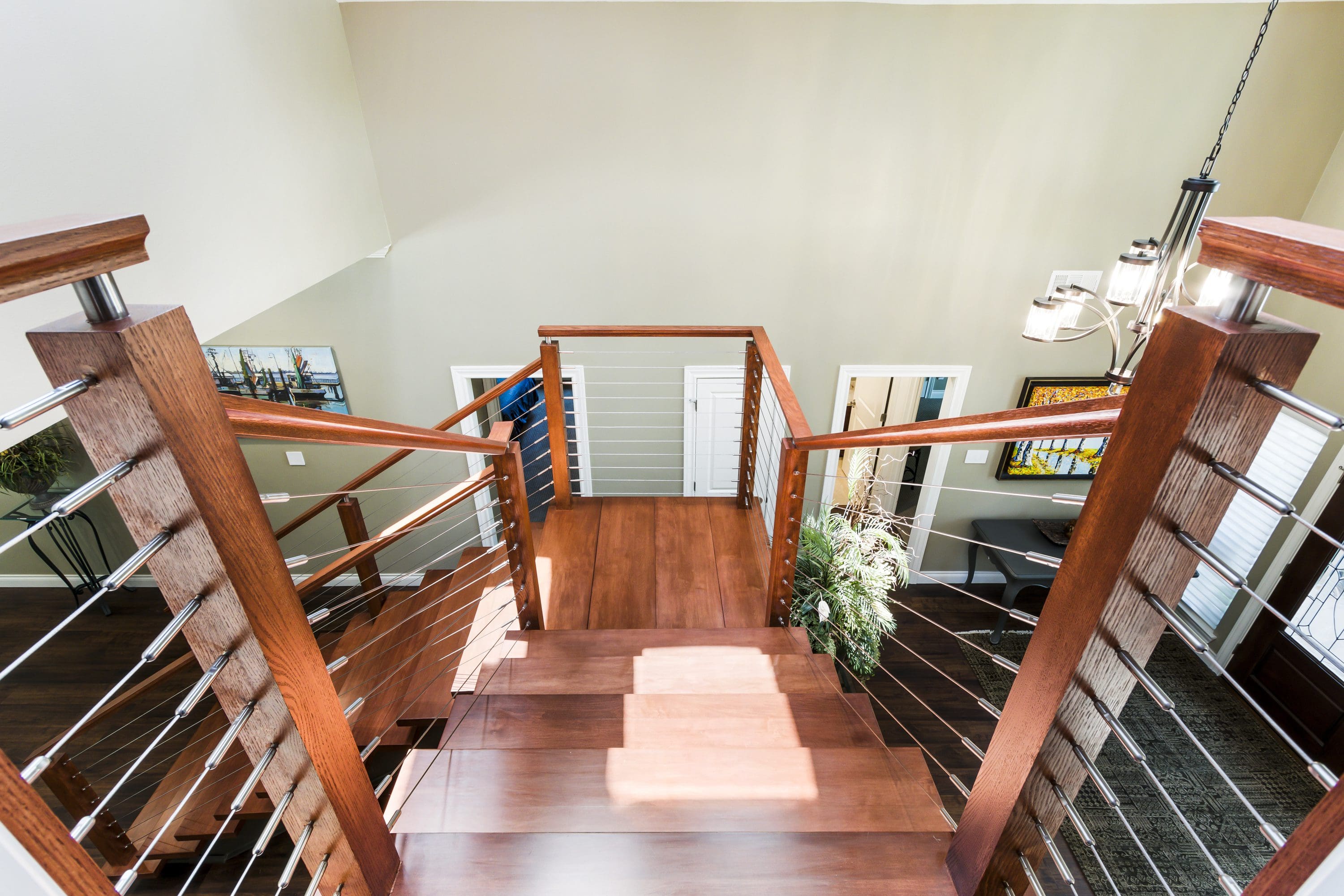 A wooden staircase with glass railing and wood handrail.