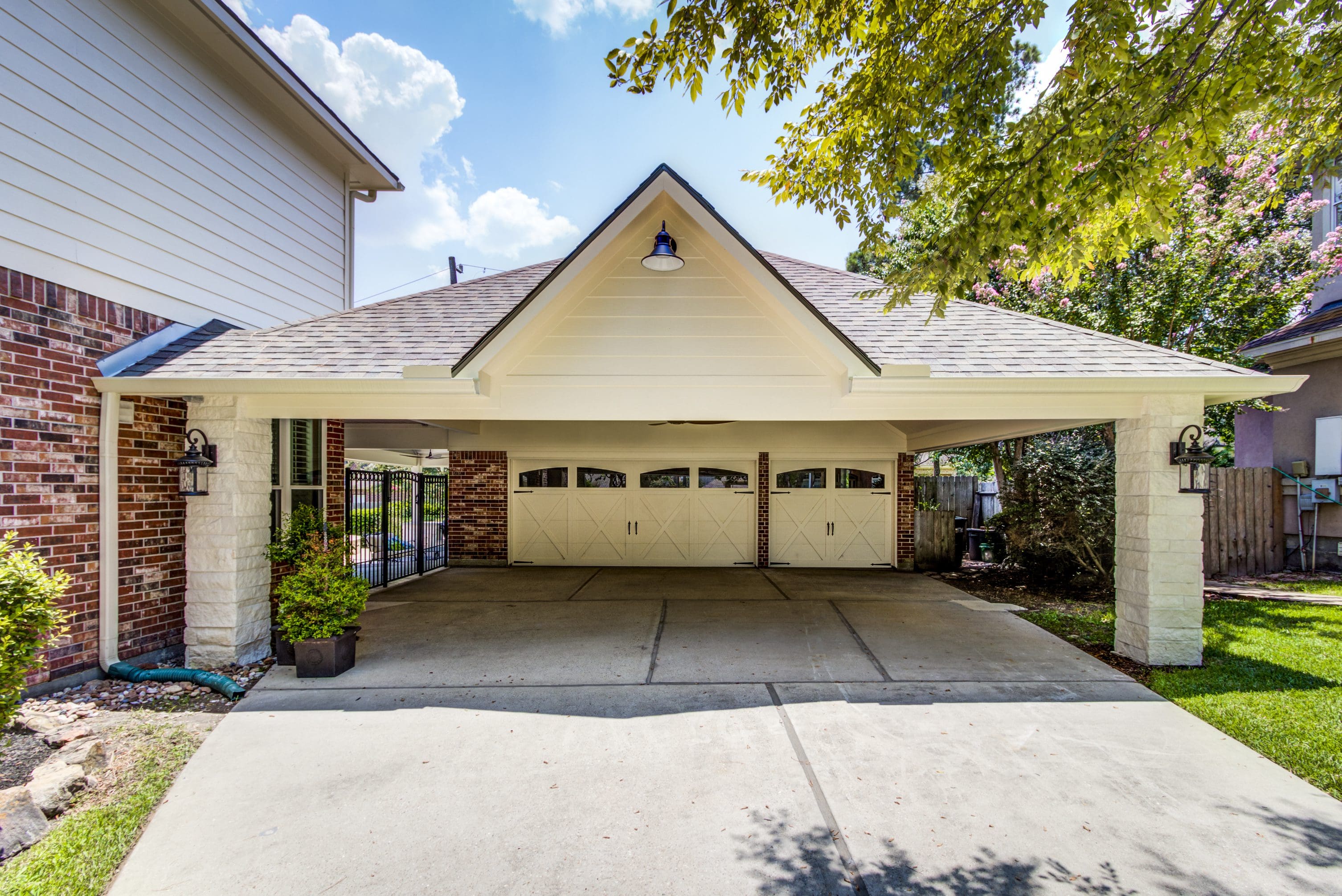 A large white garage with two doors and a carport.