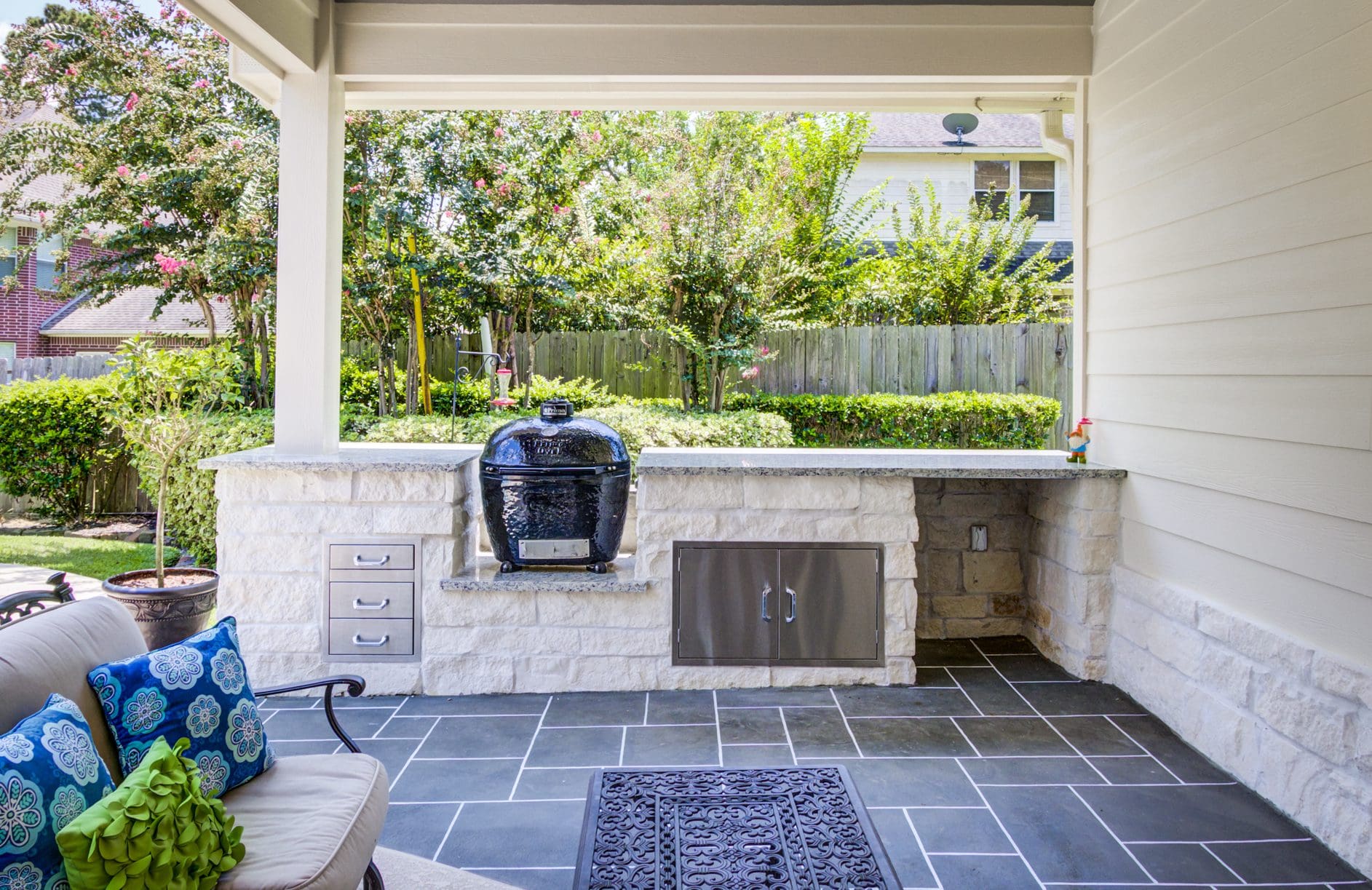 A patio with an outdoor grill and a rug.