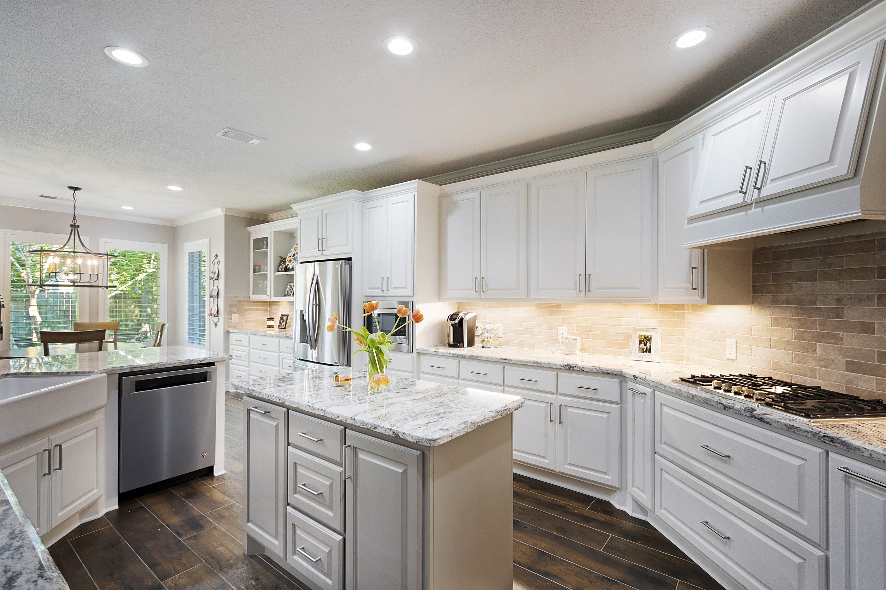 A kitchen with white cabinets and wood floors.