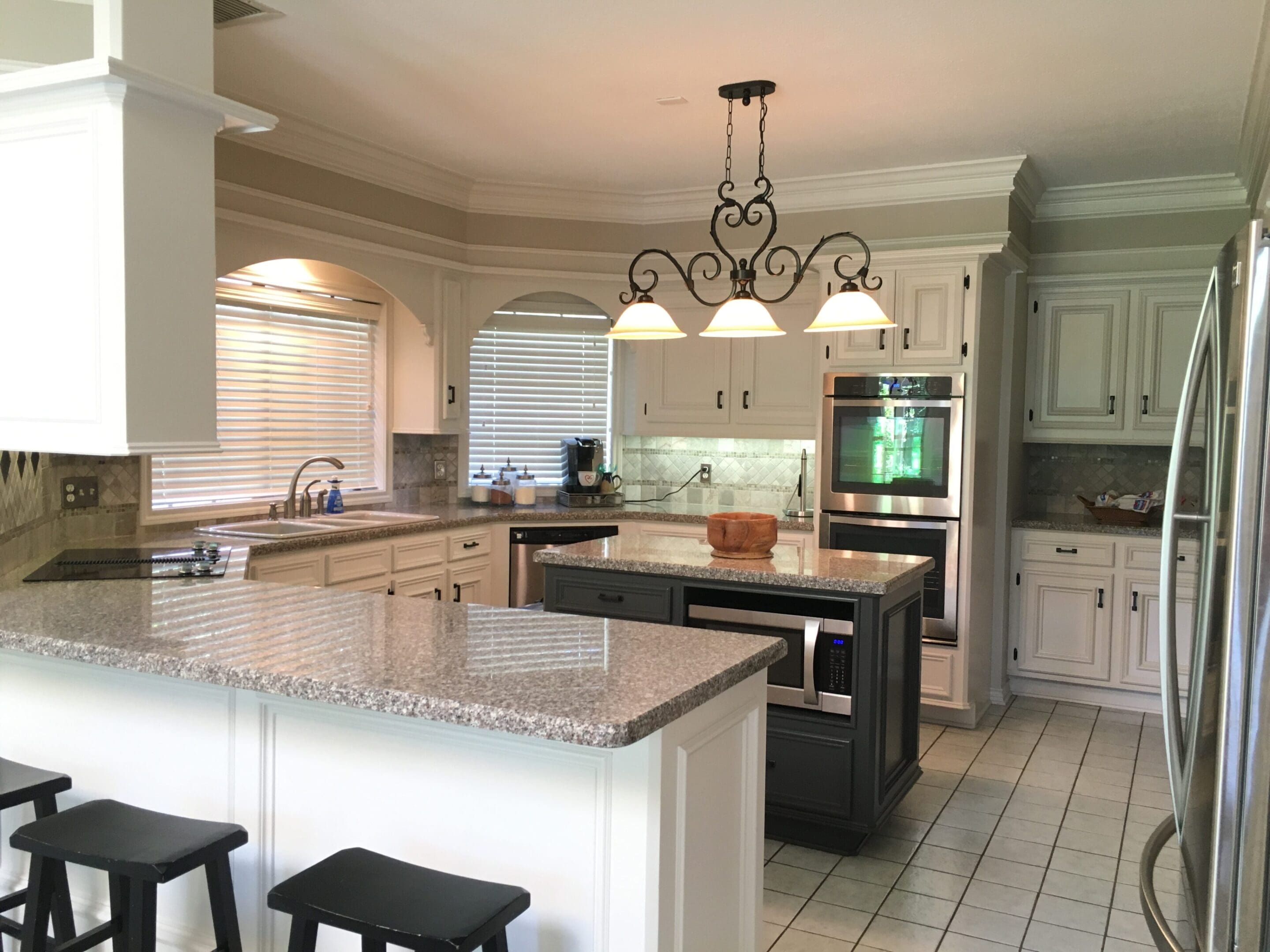 A kitchen with white cabinets and black island.