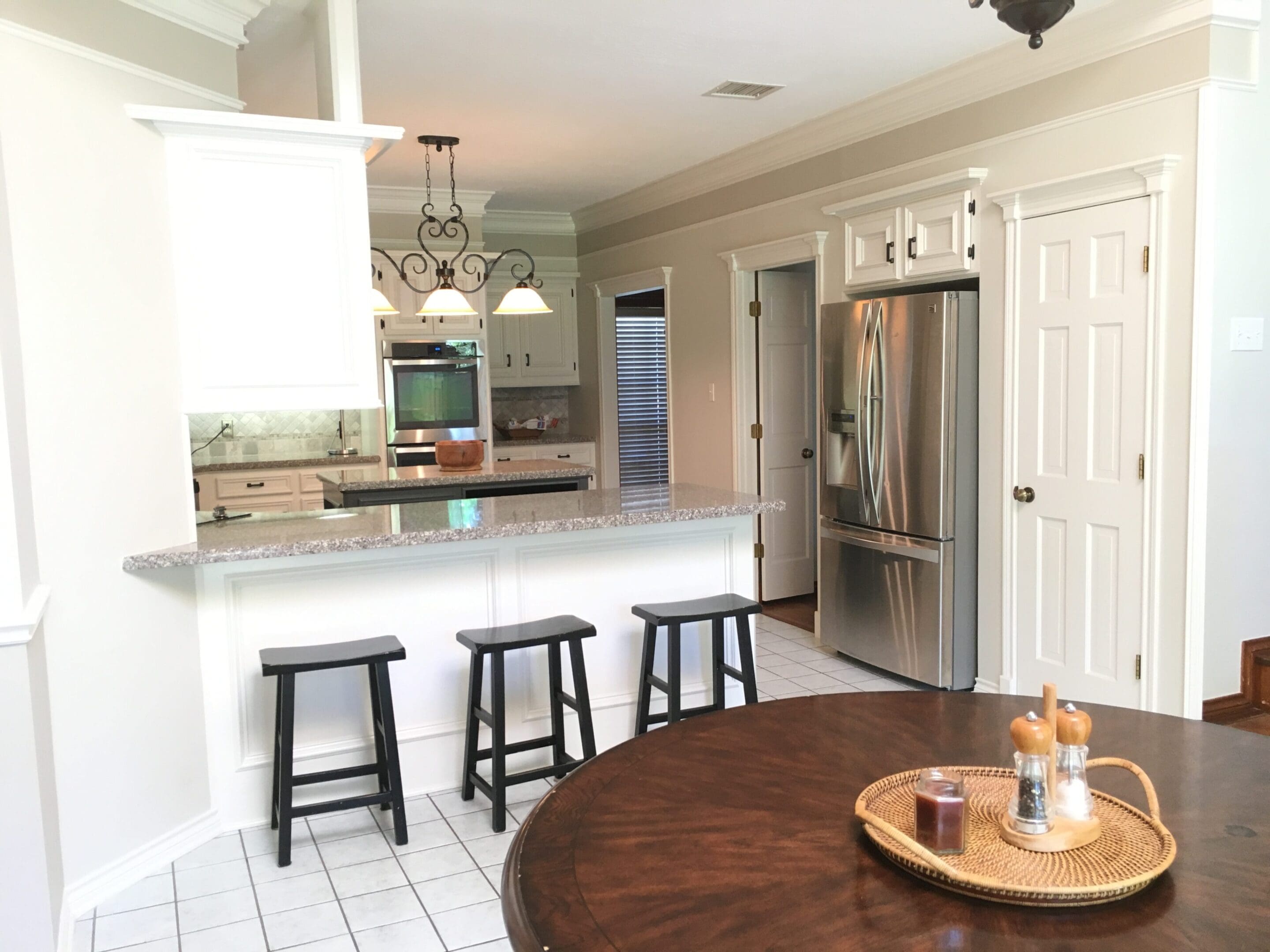 A kitchen with white tile floors and a wooden table.