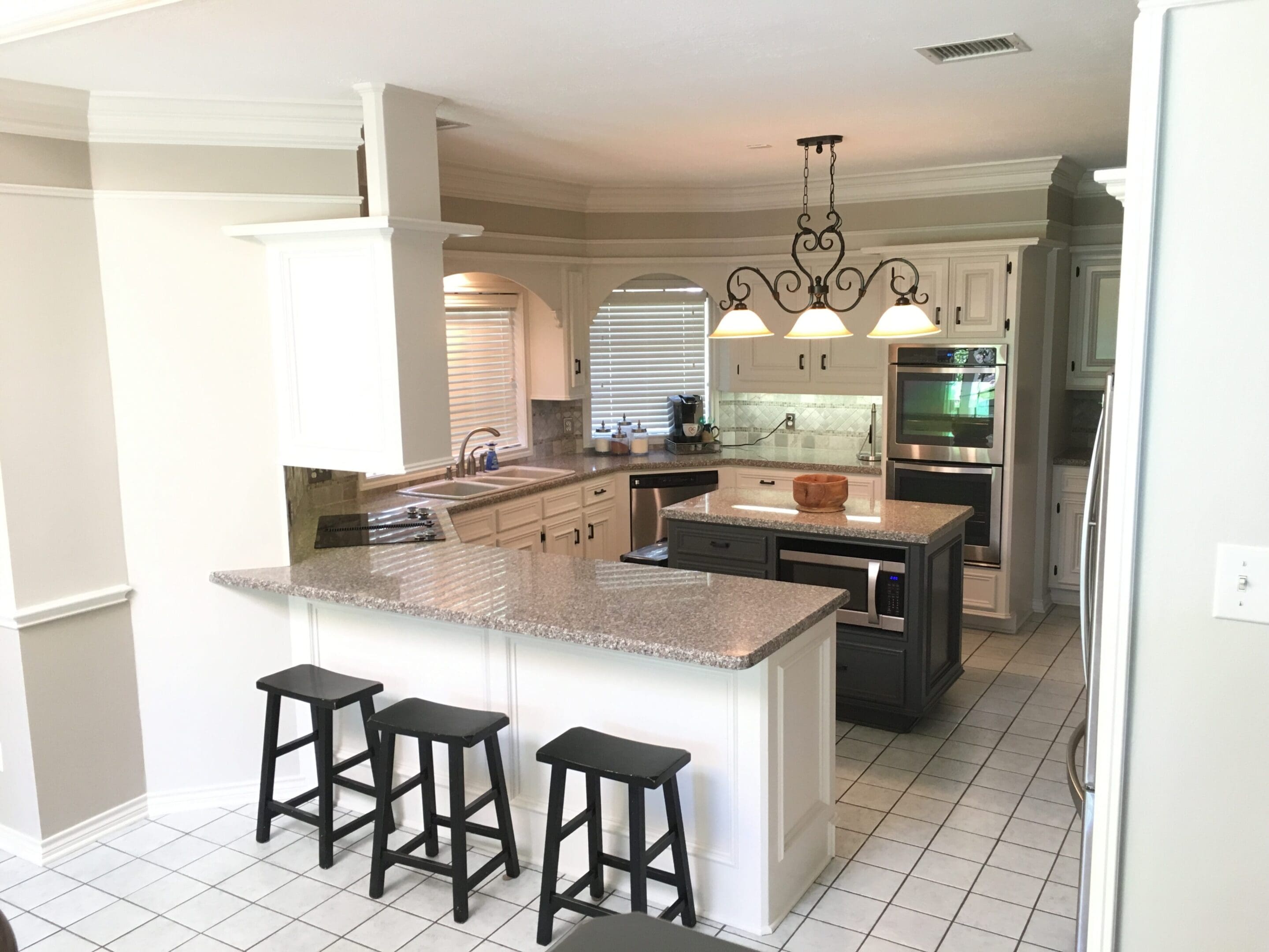 A kitchen with white cabinets and black counter tops.