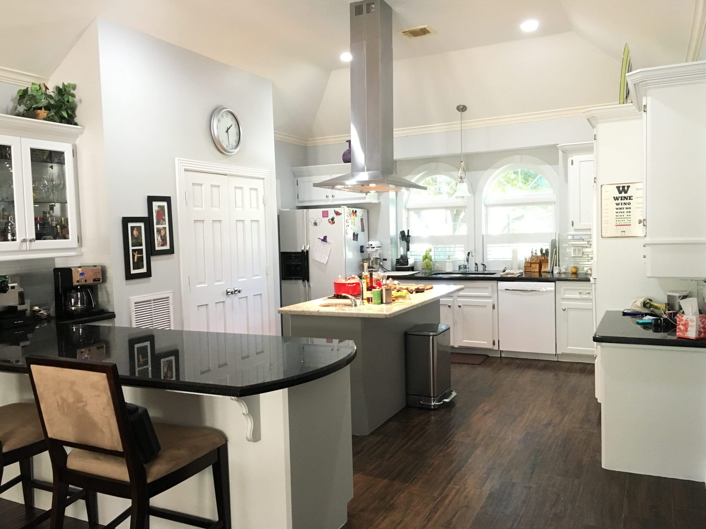 A kitchen with white cabinets and black counter tops.