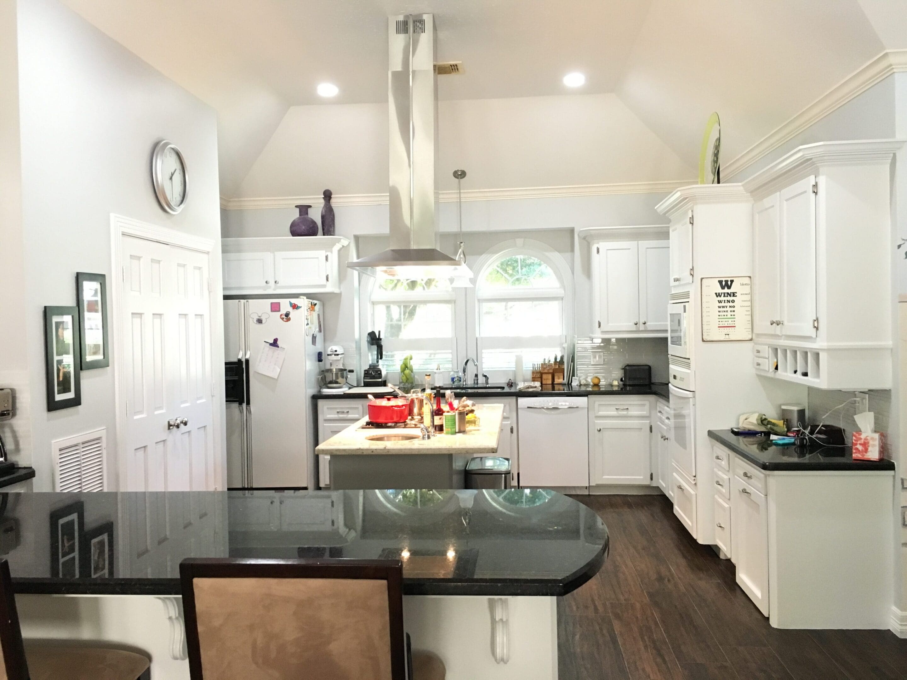 A kitchen with white cabinets and black counter tops.