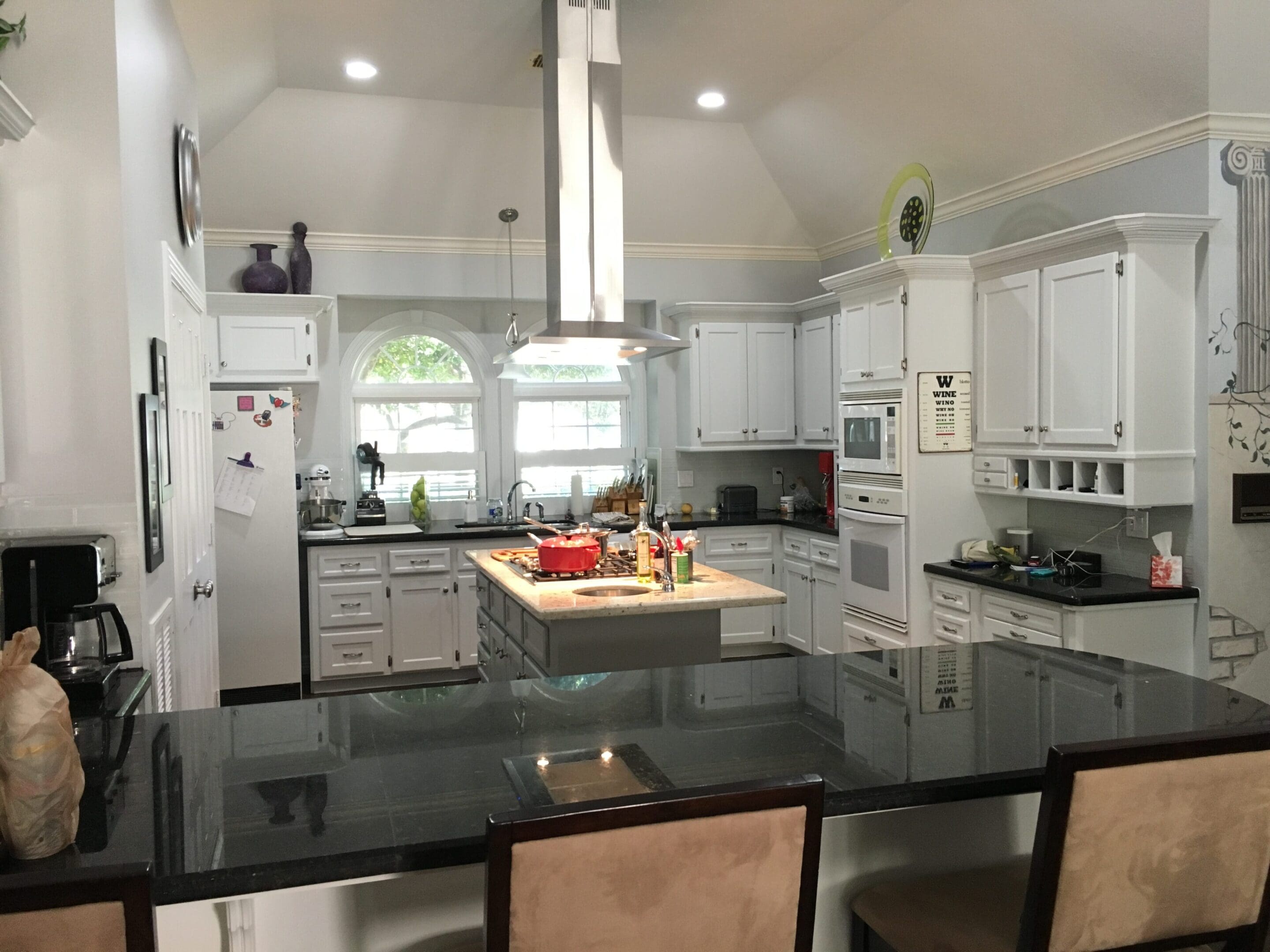 A kitchen with white cabinets and black counter tops.