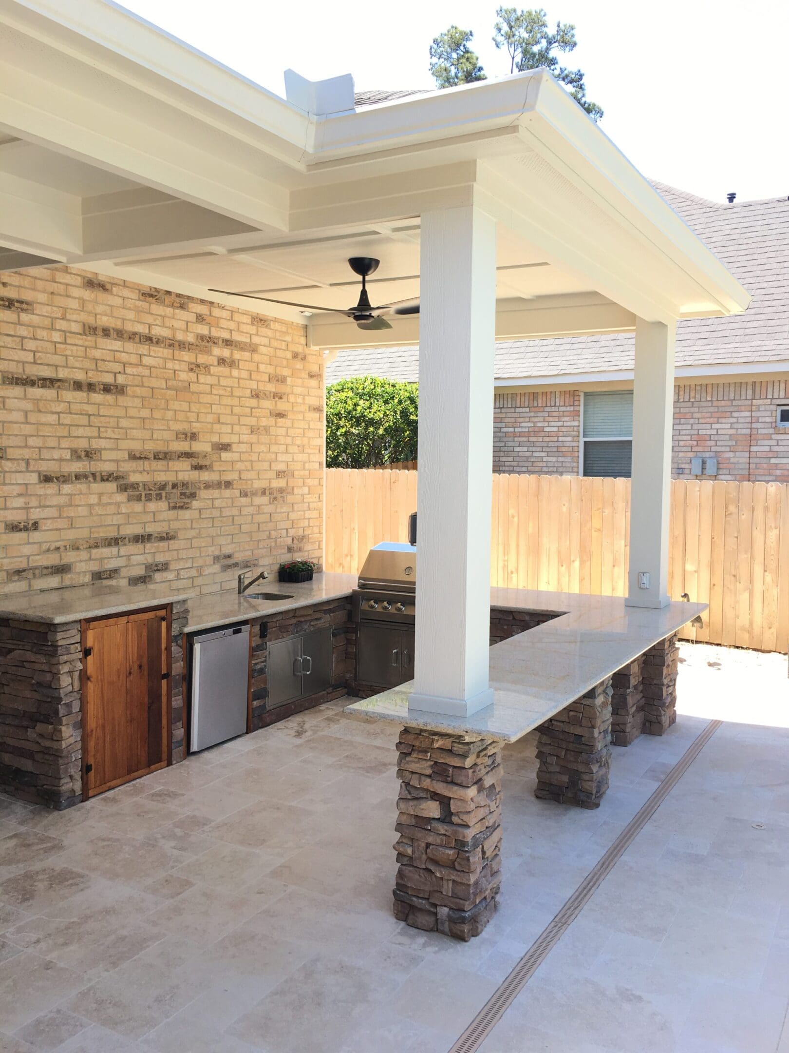 A patio with an outdoor kitchen and stone pillars.