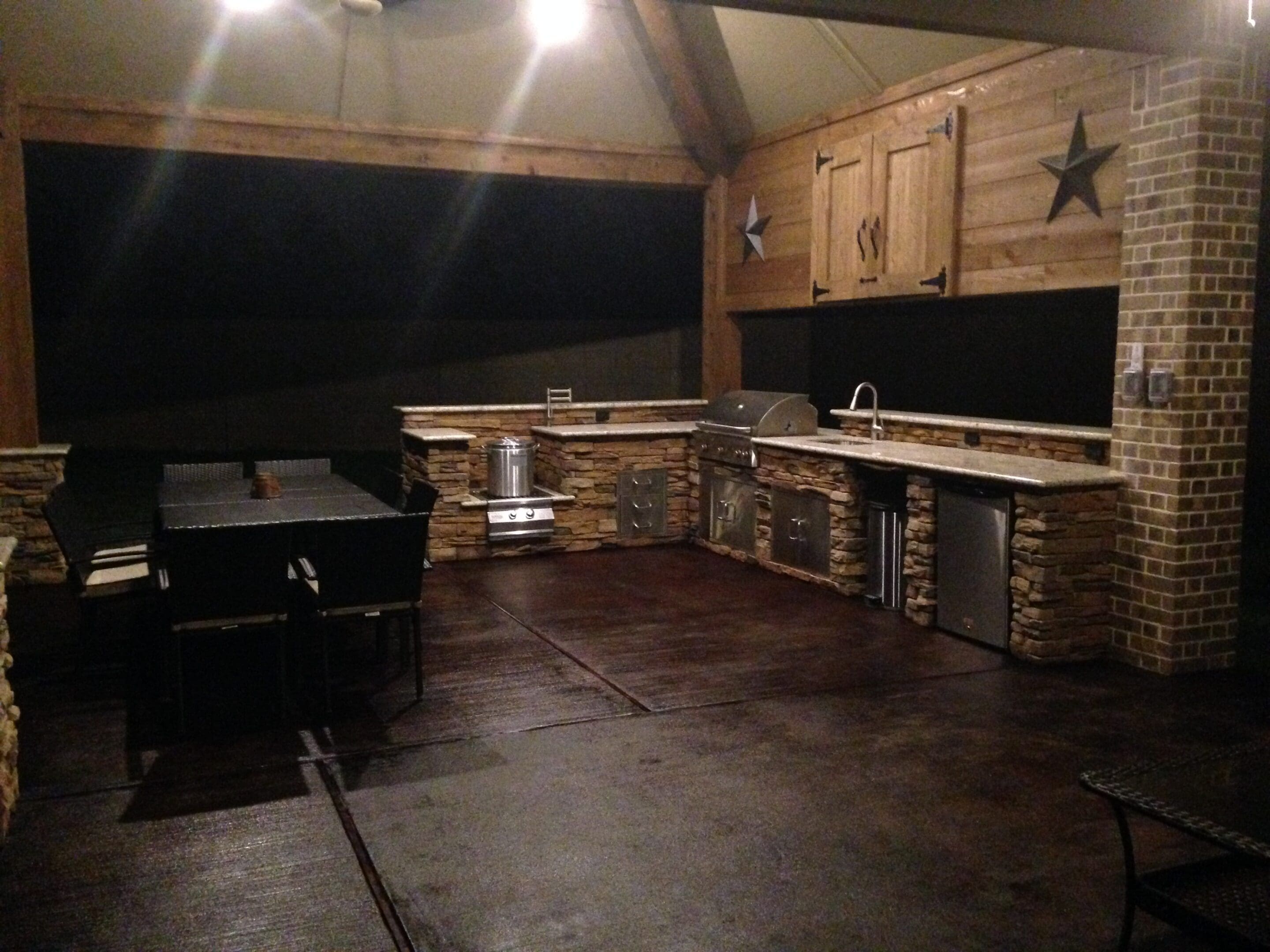 A large outdoor kitchen with a grill and sink.
