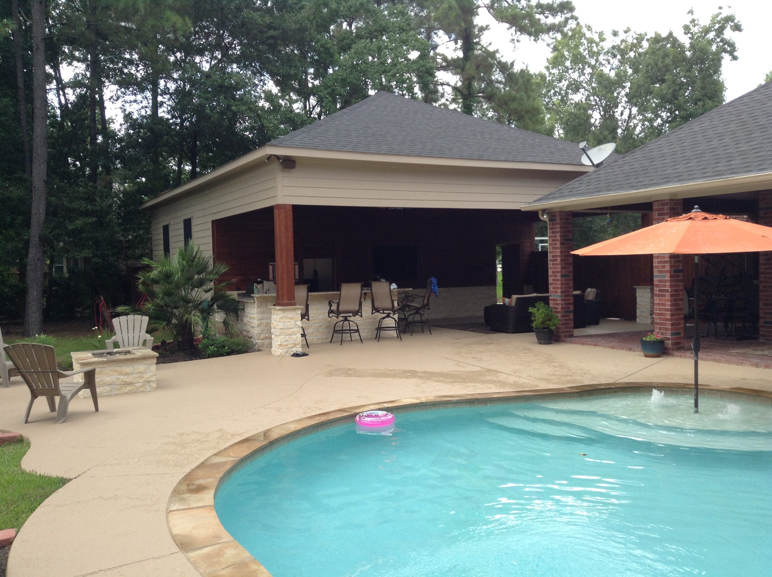 A pool with an umbrella and chairs in the back yard.