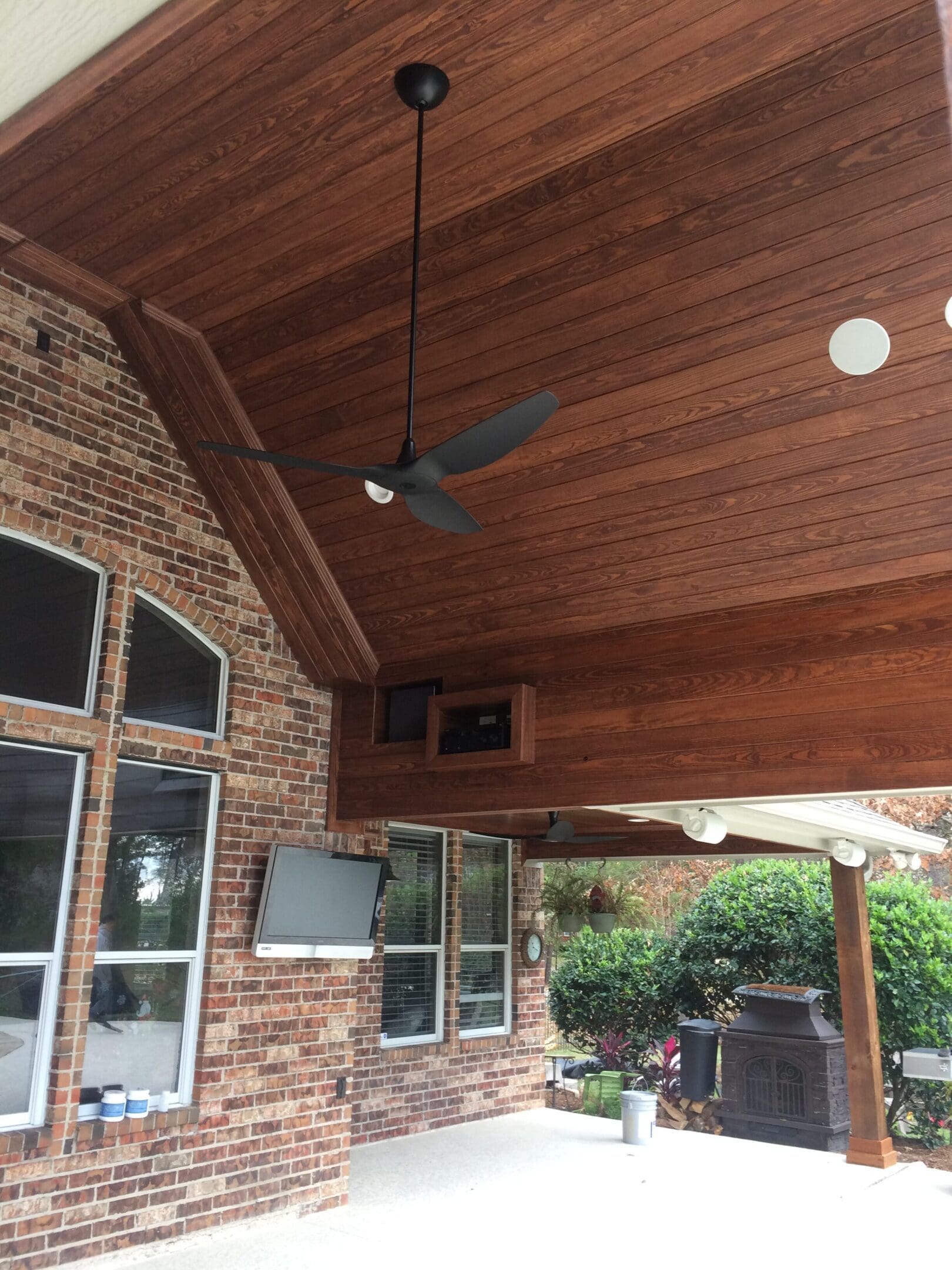 A ceiling fan in the middle of an outdoor patio.