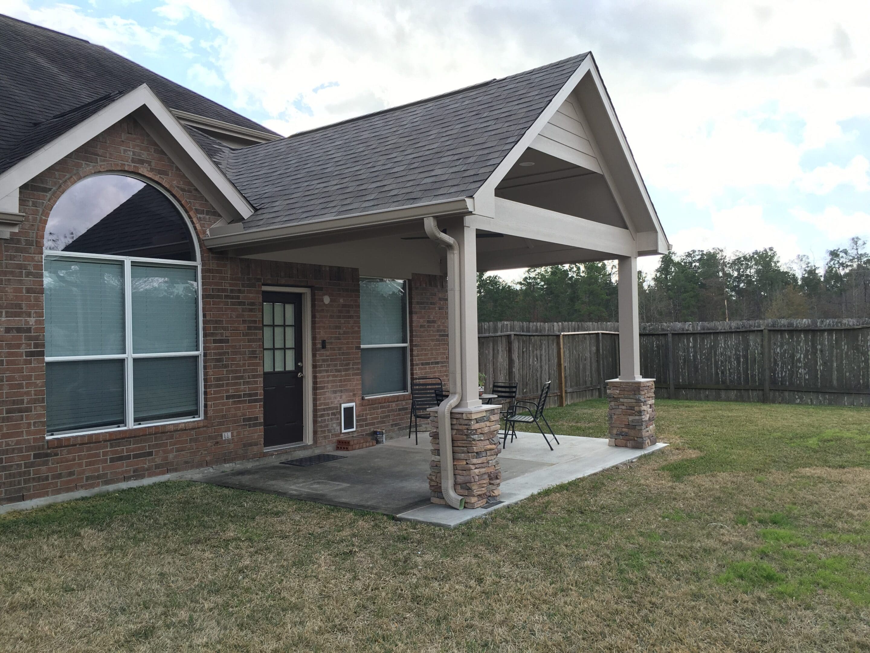 A patio with a stone wall and a brick roof.