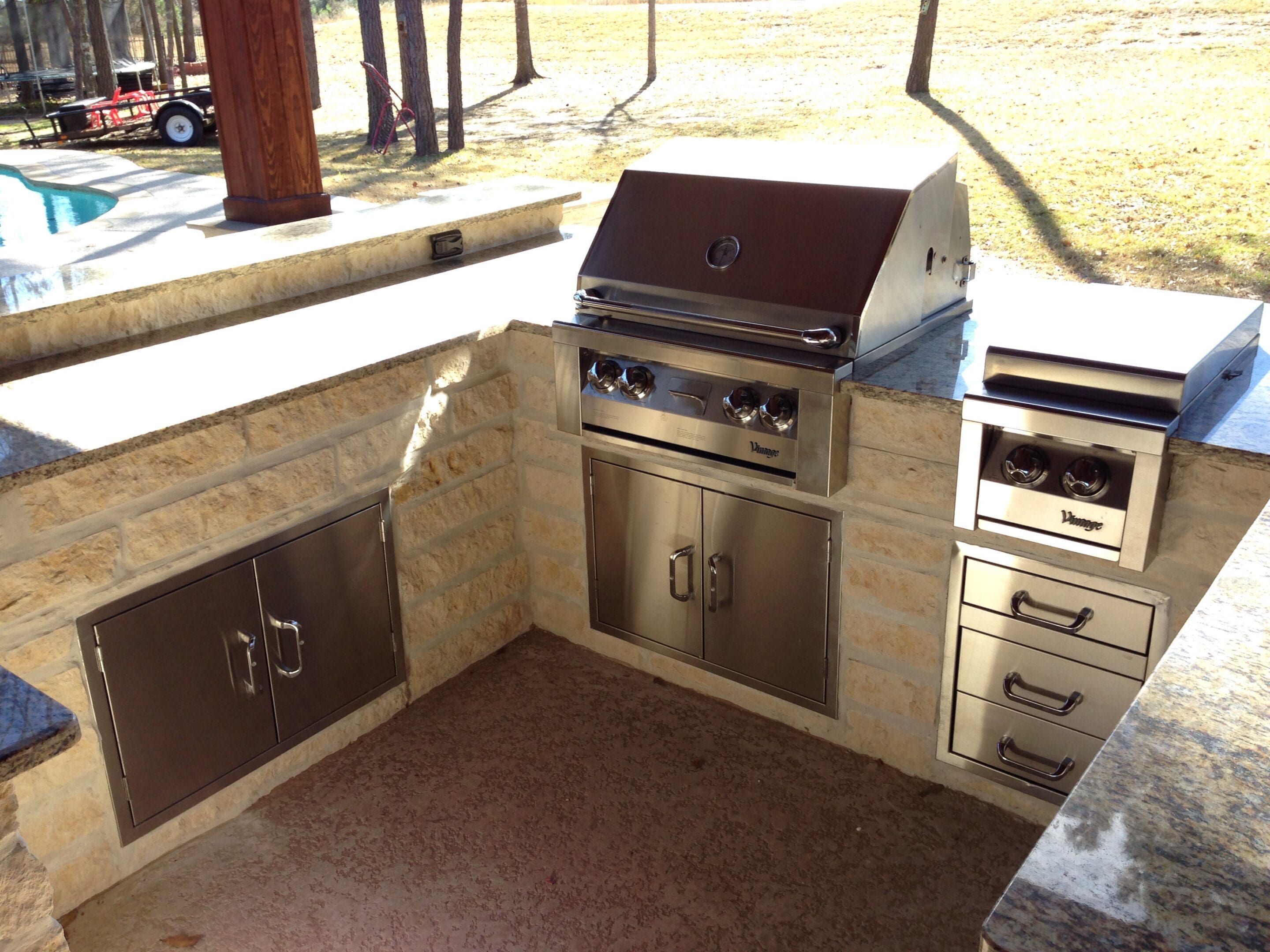 A stainless steel outdoor kitchen with an oven and grill.