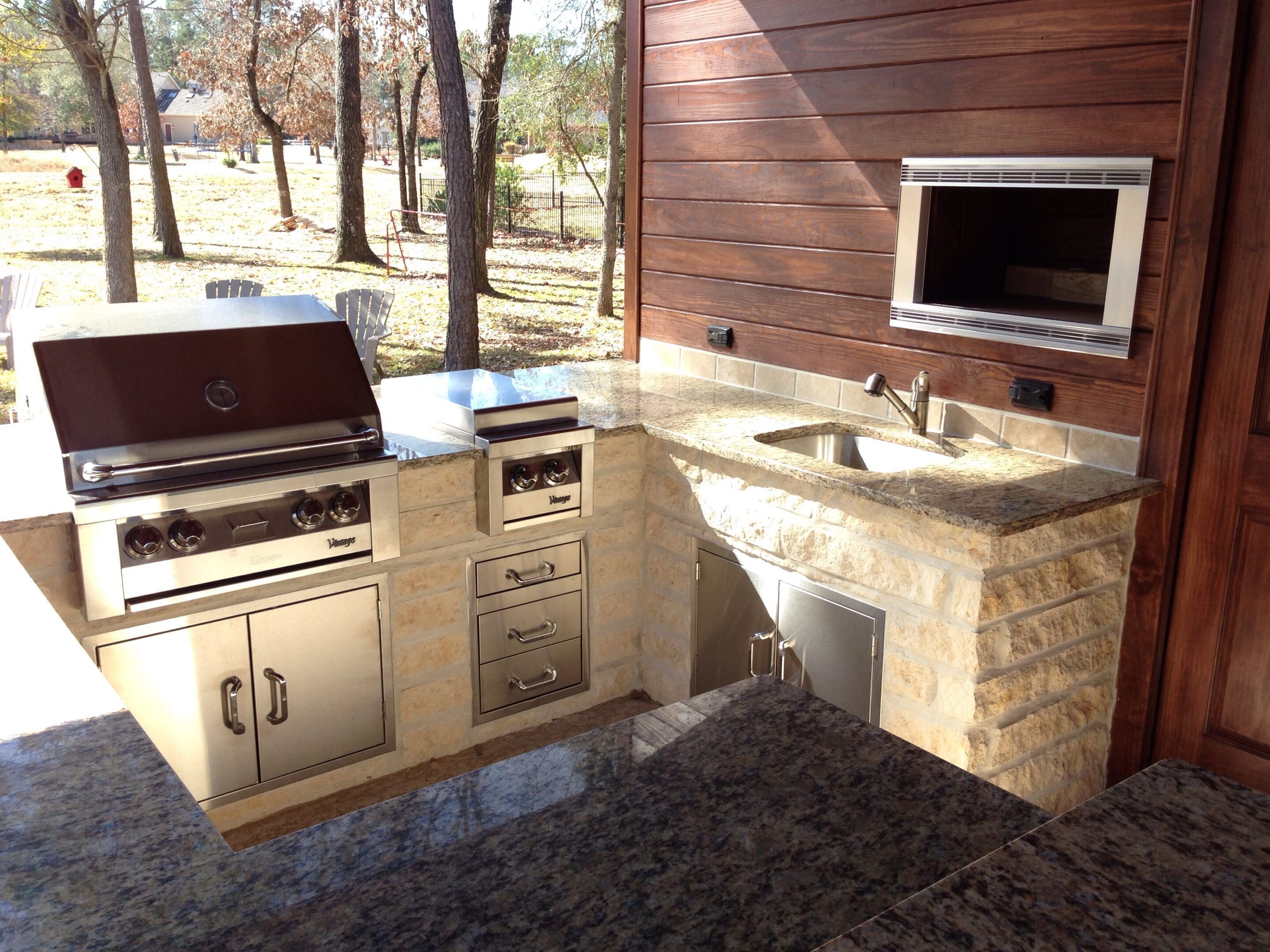 A large outdoor kitchen with sink and refrigerator.