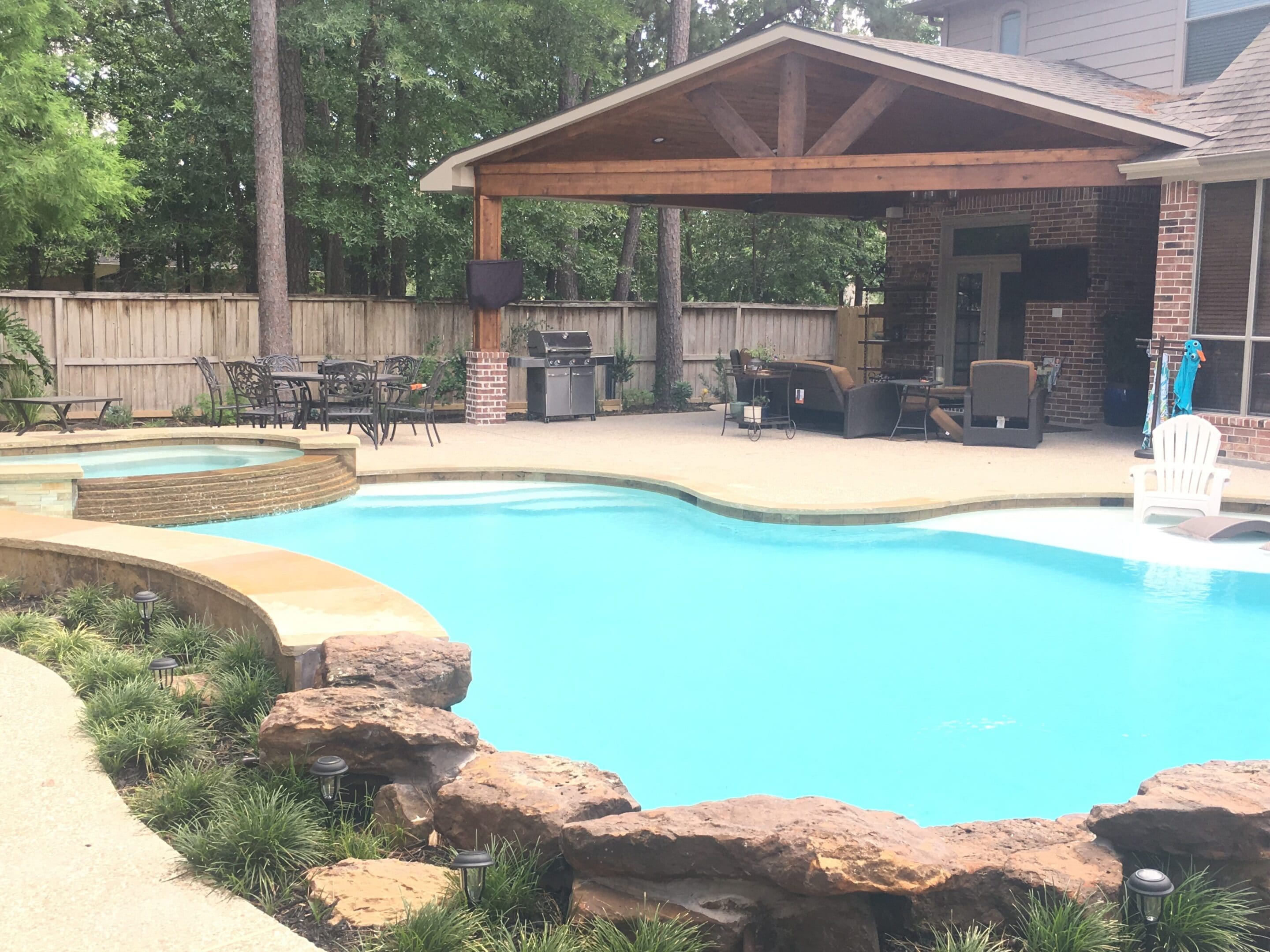 A pool with a covered area and stone wall.