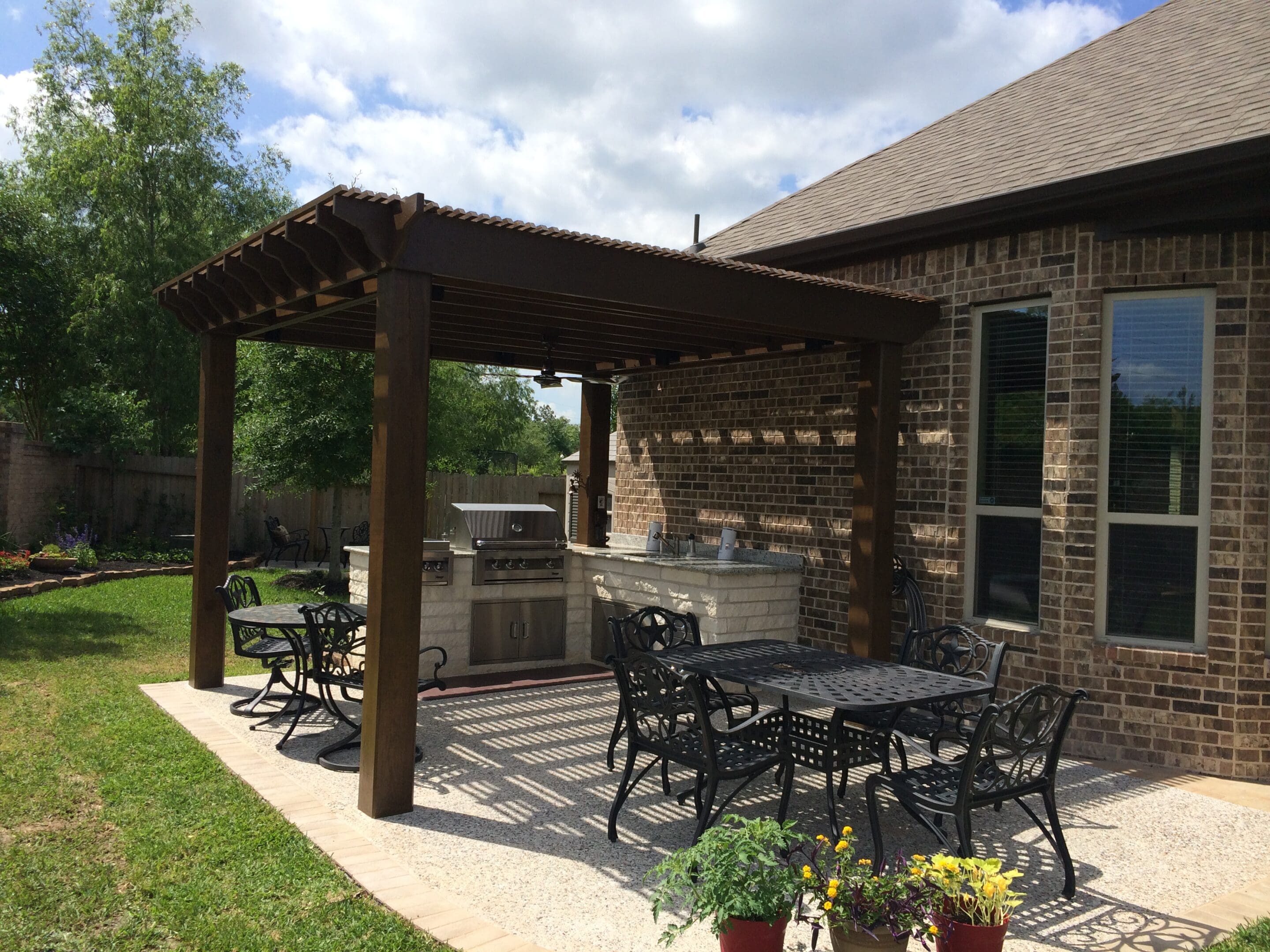 A patio with tables and chairs, grill and pergola.