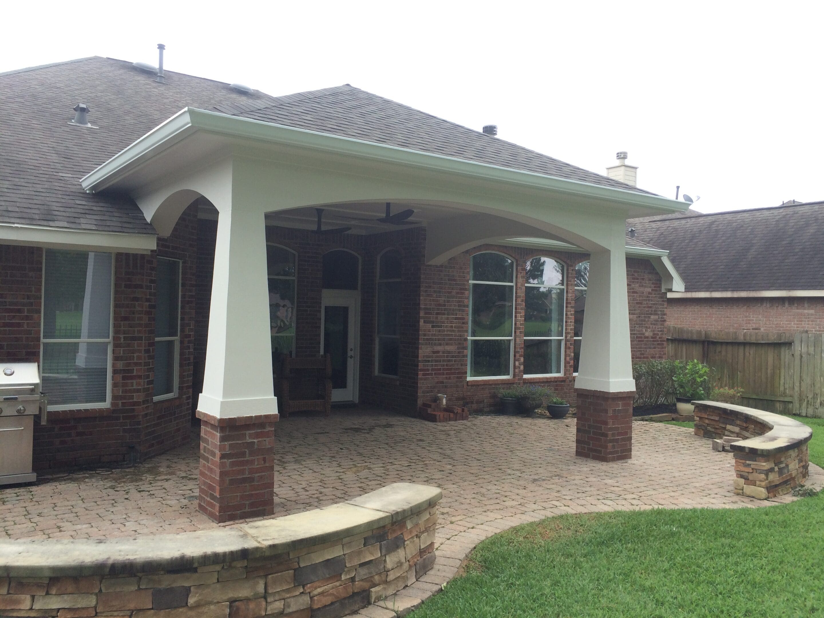 A patio with brick and stone walls in the back yard.