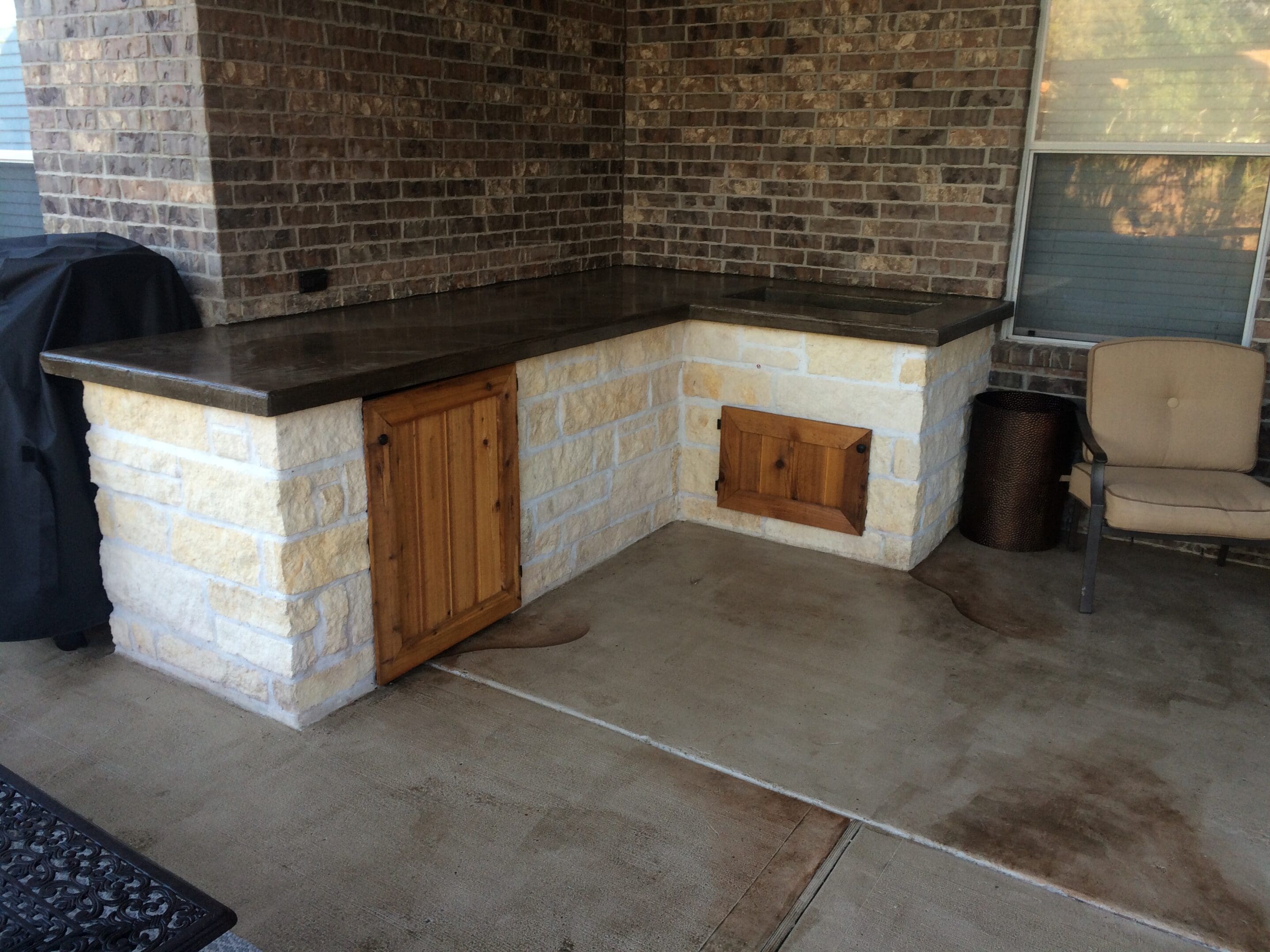 A concrete patio with an outdoor kitchen and bbq.
