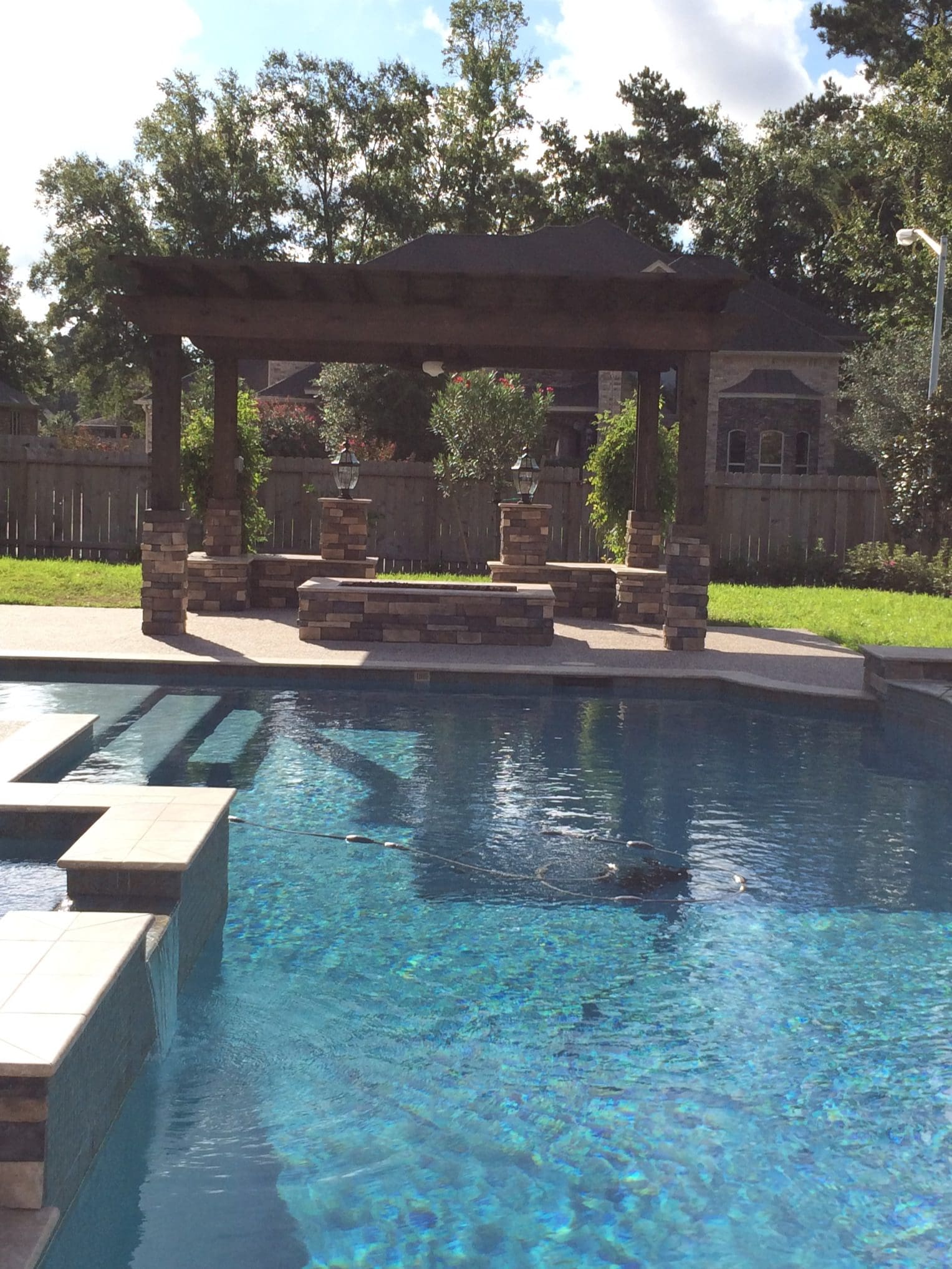 A pool with a gazebo and a stone wall.