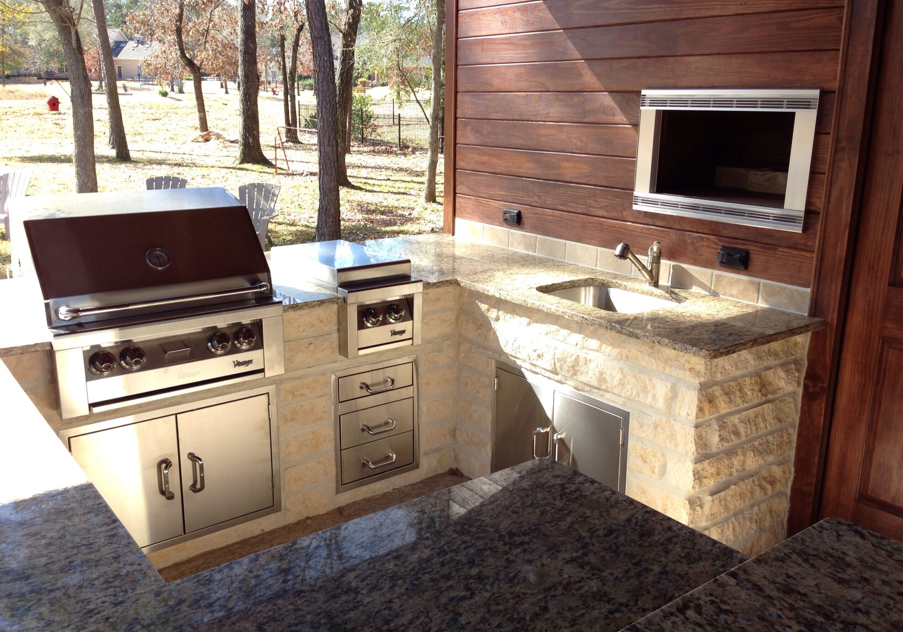 A large outdoor kitchen with sink and refrigerator.
